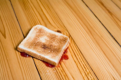 Slice-of-toast-with-strawberry-jam-upside-down-on-floor